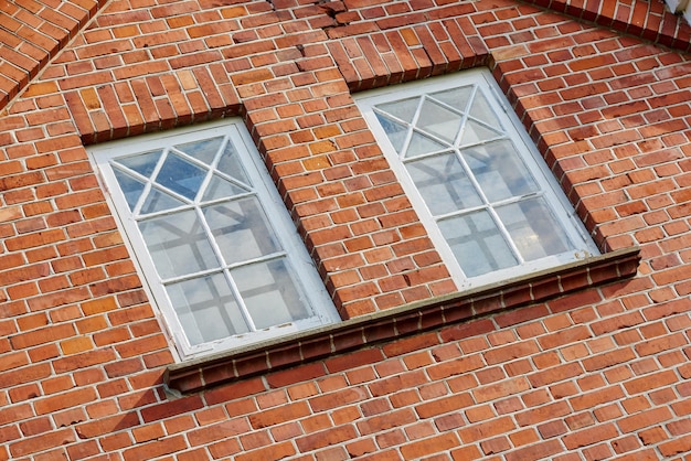 Old stone wall with two rectangular windows Close up of rectangular windows of a building with a red brick wall Patterned windows on a red stained brick wall of an old building or house