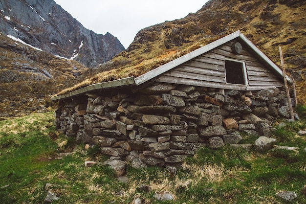 Old stone and wood house covered with moss on the background of the mountains