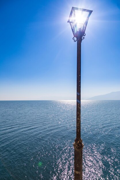 Old street lamp with sunbeams coming through with seascape background