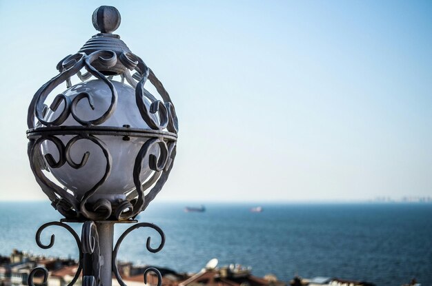 Photo old street light by sea against clear sky