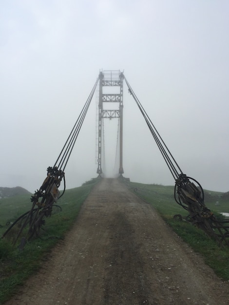 Foto vecchio ingresso del ponte sospeso alla nebbia. ponte del villaggio di altai. mattina presto nebbiosa