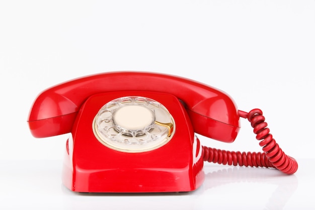 Old telephone in red color isolated on white surface