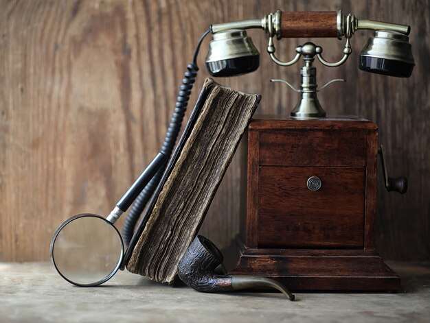 Old telephone and retro book on a wooden table