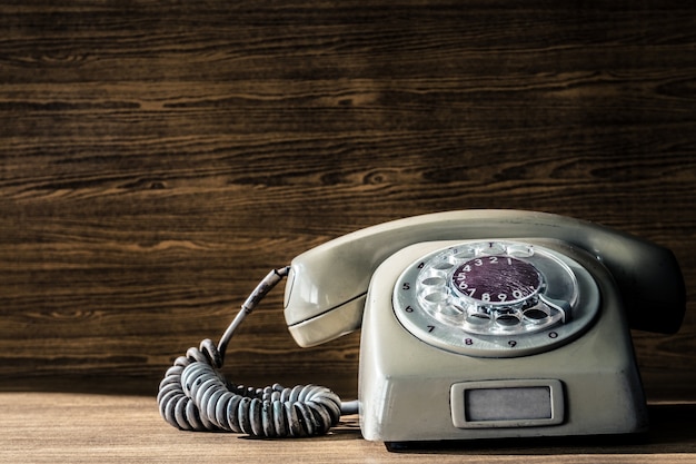 Old telephone on wooden table background. 