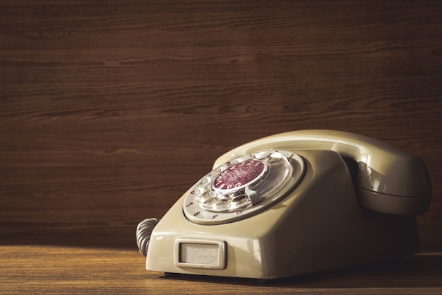 Old telephone on wooden table background. 