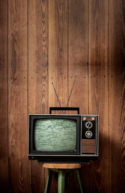 old television set on stool against wooden wall