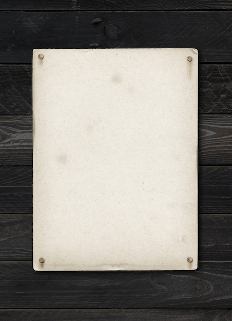 Old textured paper sheet nailed on a black wood table. vertical Mockup