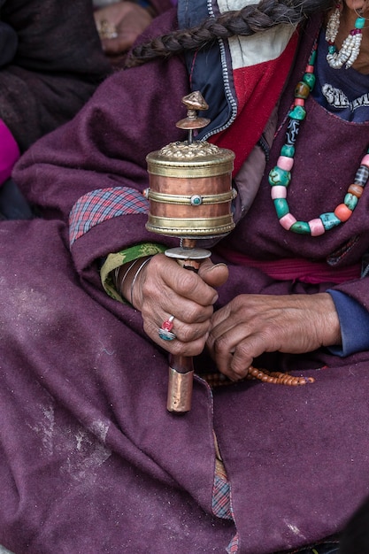 Old tibetan woman holding buddhist prayer wheel in monastery, Ladakh, India, close up