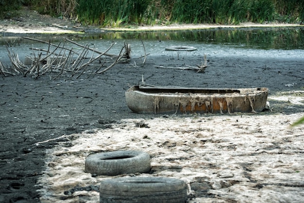 Старая шина на берегу реки Проблемы с вывозом мусора Загрязнение окружающей среды