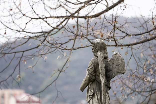 Old tombstone sculpture of an angel with broken arm and wings on the cemetery