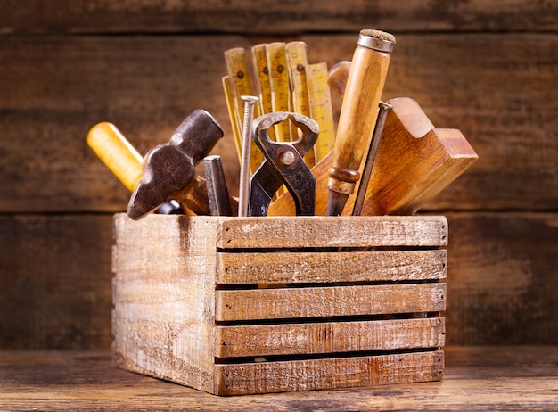 Old tools in a wooden box on wooden background