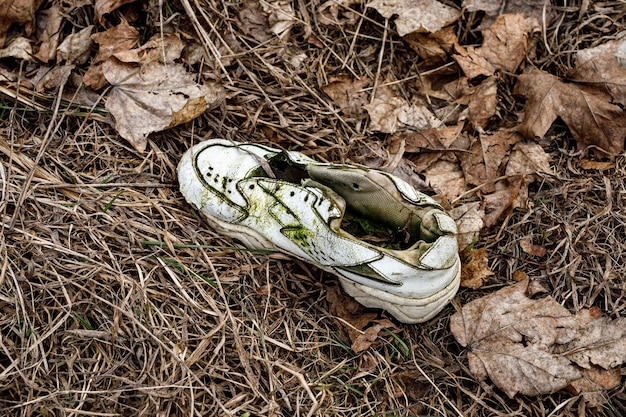 Old torn sneakers in dirty grass.