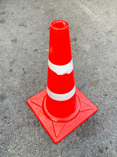 Old traffic cone standing on the asphalt road