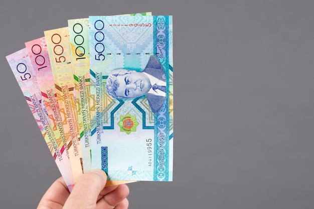 Старые туркменские деньги в руке на сером фоне