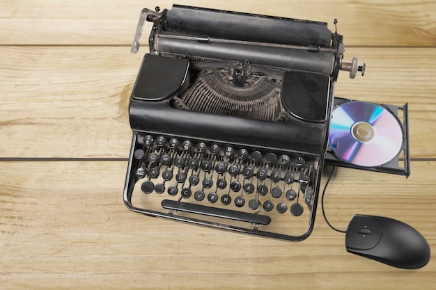 Старая пишущая машинка с компьютерным диском и мышью на фоне