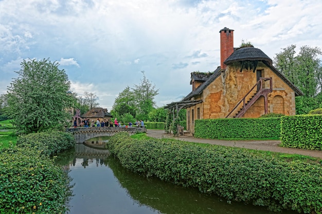 Photo old village of marie antoinette and the palace of versailles in paris in france. people on the background