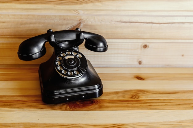 Old vintage black phone on wooden table.