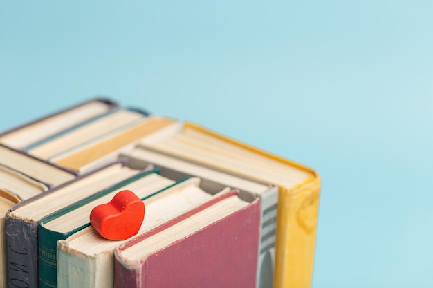 Old vintage books and little red heart on the light blue background World Book Day Copy space