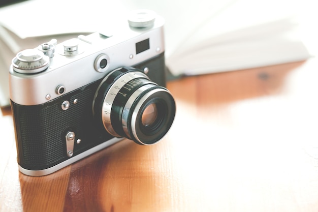 Old vintage camera with book on a wooden table.