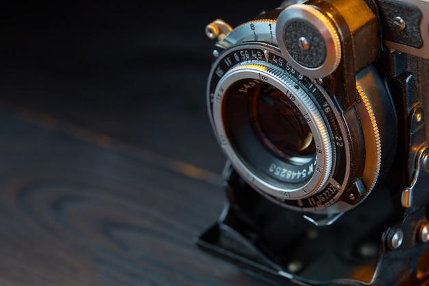 Old vintage camera on the wooden table. Cinematic style.