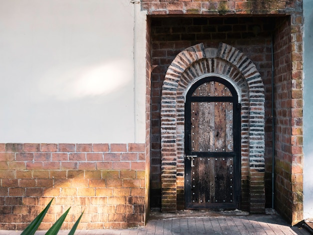 Photo old vintage curved wooden door ornamented with bricks on concrete building with copy space.