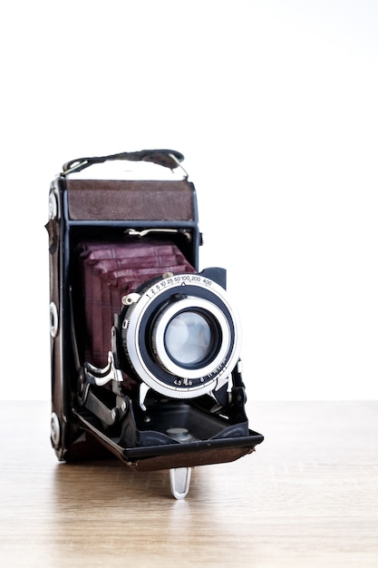 Old vintage photo camera on table and white