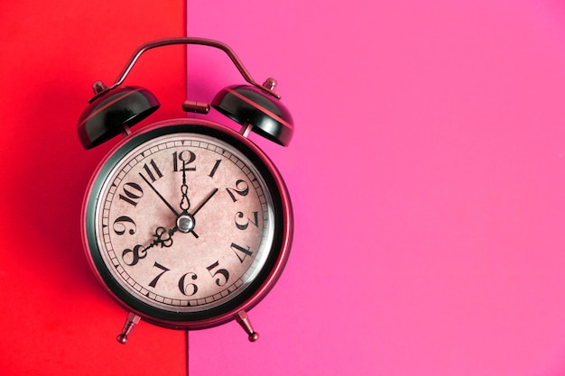 Old, vintage retro alarm clock on a bright red background.