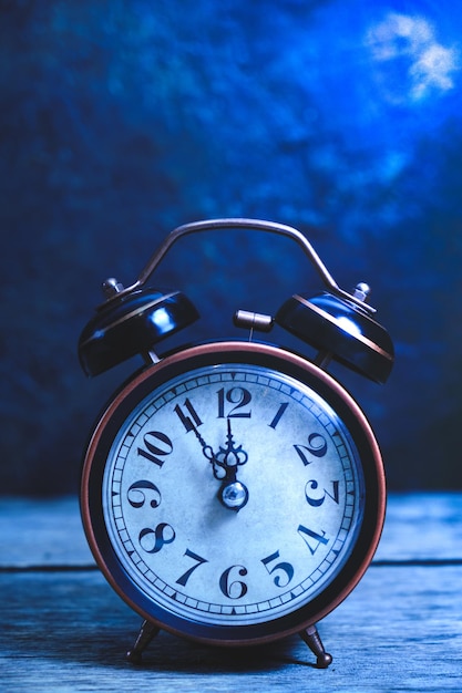 Old, vintage, retro alarm clock on wooden table at night in moonlight.