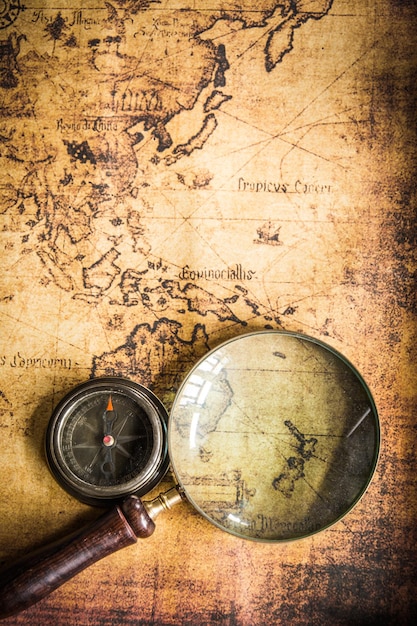 Old vintage retro compass and magnifying glass on ancient mapThe map used for background is in Public domain