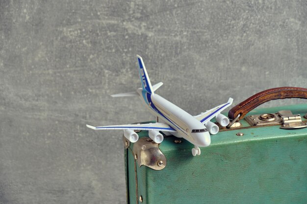 写真 古いビンテージ レトロなスーツケースとおもちゃの飛行機概念の休暇と旅行