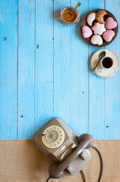 写真 古いビンテージ電話、ビスコッティ、コーヒー、木製の背景にドーナツ