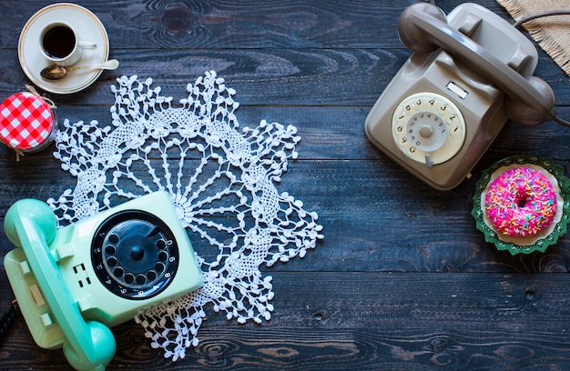 Old vintage telephone, with biscotti, donuts on a wooden background, free space for text