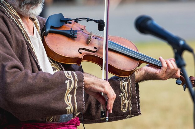 Old violinist plays the violin in front of the microphone_