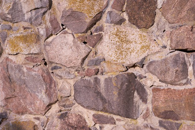 Un vecchio muro di pietre di granito di diverse dimensioni come sfondo.