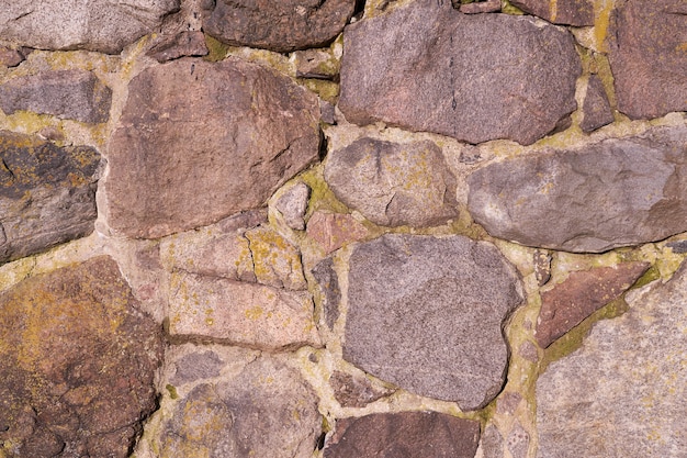 An old wall of granite stones of different sizes as a background.