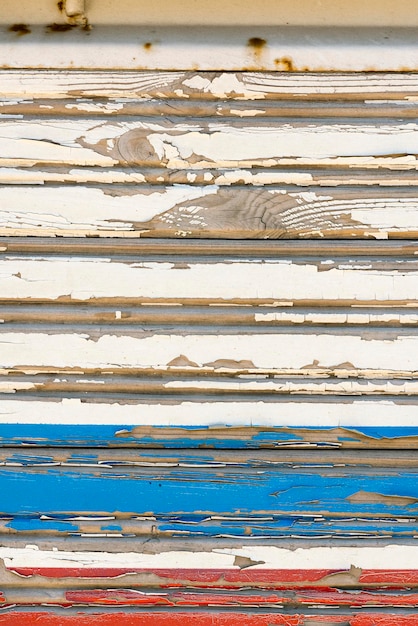 Old wall of wooden planks with a cracked blue red and white paint