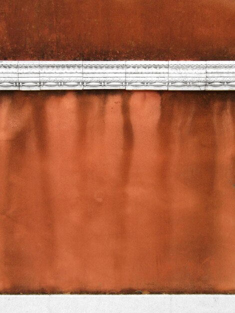 Photo old weathered orange wall with decorated stone cornice background