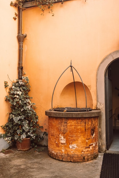 An old well near the orange wall of a house on an old street in italy high quality photo