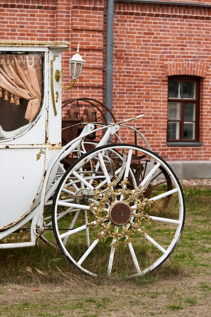 Old white carriage on the background of a red brick building. White vintage carriage