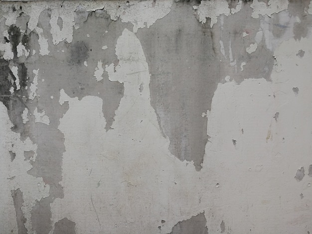 Old white concrete wall with paint cracks. Background texture