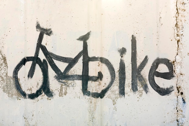 Old white wall with black painted bicycle and the words BIKE