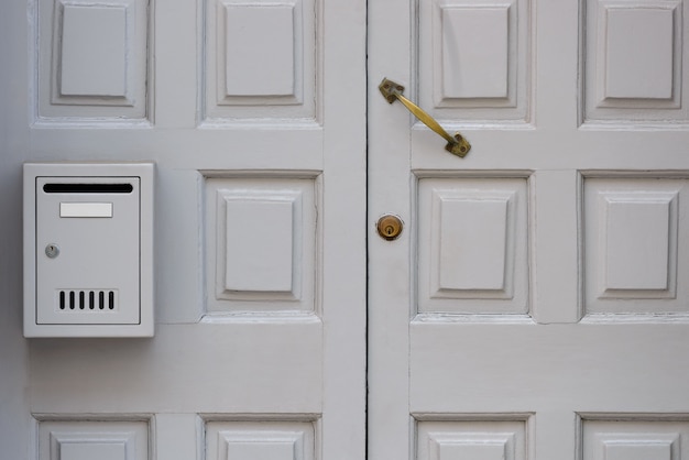 Old white wooden door with mailbox close-up