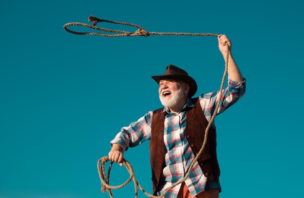 Old wild west cowboy with rope bearded western man throwing lasso with brown jacket and hat catching