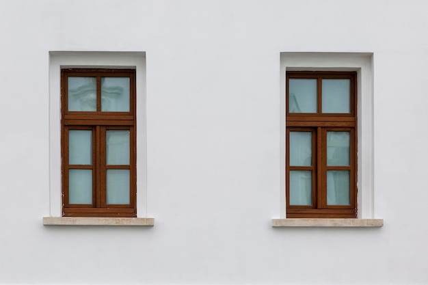 Old windows with wooden frames in a white brick house Front view Historical architecture