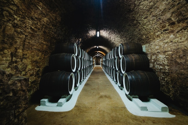 Old wine oak barrels in a wine cellar stored in a winery