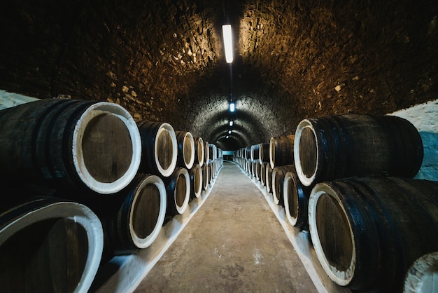 Old wine oak barrels in a wine cellar stored in a winery