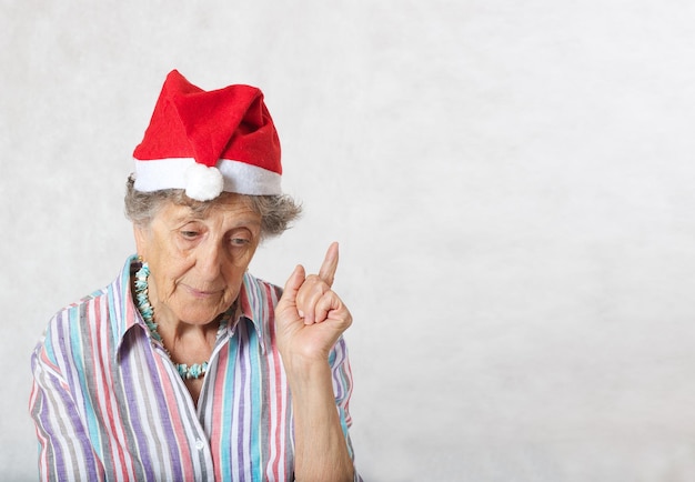 Old woman between 70 and 80 years old in the hat of a santa claus