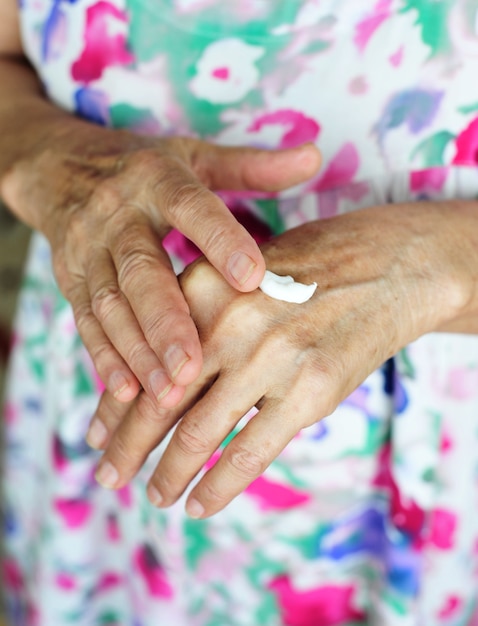 Old woman applying moisturizer