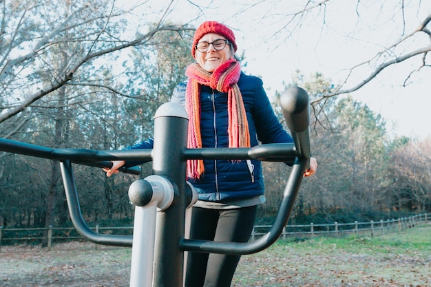 Пожилая женщина делает тренировку в парке на тренажерах, чтобы поддерживать суставы в хорошем состоянии Довольна здоровым образом жизни Спорт на природе Пожилые люди Подготовка рук и ног для пожилых людей