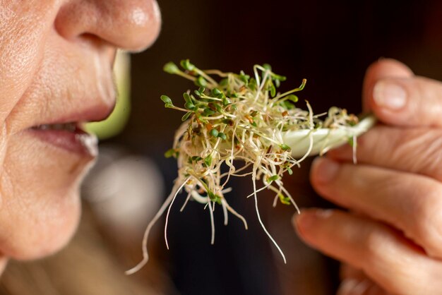 An old woman eats sprouted radish seeds in a spoon